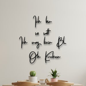 Könnte beinhalten: Schwarze Wanddekoration mit dem Text "Ich bin so satt, ich mag kein Bl... Oh Kuchen" in handschriftlicher Form.