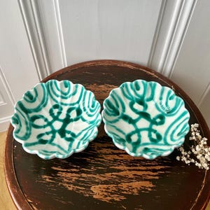 May include: Two white ceramic bowls with a scalloped edge and a green and white geometric pattern.