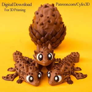 May include: A collection of 3D-printed dragon figurines in shades of brown, with large white and black eyes. The dragons are arranged in front of a larger, egg-shaped object. The text "Digital Download For 3D Printing" and "Patreon.com/cylix3D" are visible.