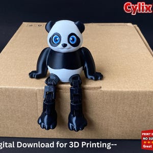 Peut inclure: Une figurine d'ours panda noir et blanc imprimée en 3D avec des yeux bleus. Le panda est assis sur une boîte en carton marron avec le texte "--Téléchargement numérique pour l'impression 3D--" imprimé sur le devant. Le texte "Cylix 3D" est imprimé en rouge sur le dessus de la boîte.