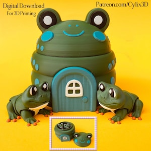 May include: A whimsical green frog-shaped house with a blue door and two frog figurines. The house has a smiling face and blue accents. The image also includes a smaller frog house and frog head. Text on top reads "Digital Download For 3D Printing" and "Patreon.com/Cylix3D".