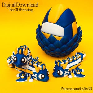 May include: A 3D-printed design featuring a blue, white, and yellow volleyball-themed egg and two dragon-like figures. The egg is nestled in a blue, petal-like structure. The figures have a similar colour scheme. Text reads "Digital Download For 3D Printing".