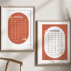 Peut inclure: Deux affiches encadrées présentant les caractères japonais Hiragana et Katakana. L'affiche Hiragana présente un ovale rouge avec des caractères blancs et le mot "HIRAGANA". L'affiche Katakana a un design similaire avec le mot "KATAKANA".