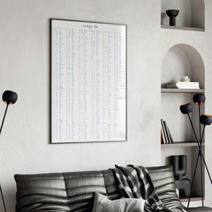 May include: A framed poster with the text "Vocabulary Hub" in blue, hanging on a white wall. The room features a black leather sofa, black and gold lamps, and built-in shelves with decorative items.