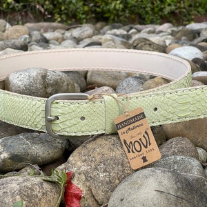 Könnte beinhalten: Hellgrüner Ledergürtel mit Schlangenmuster und silberfarbener Schnalle. Der Gürtel hat eine cremefarbene Innenseite und ein Etikett mit der Aufschrift "HANDMADE in Mallorca" und "MOVI Leather 100%."