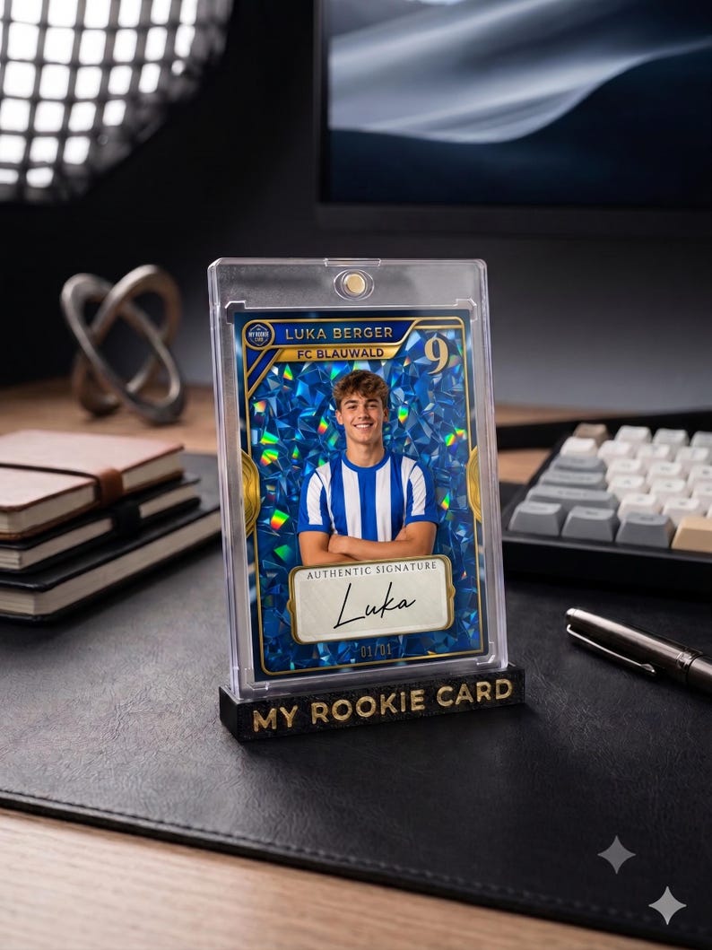 May include: A rectangular trading card featuring a portrait of a soccer player in a blue and white striped jersey, set against a blue holographic background. The card displays the text Luka Berger, FC Blauwald, and an authentic signature label.