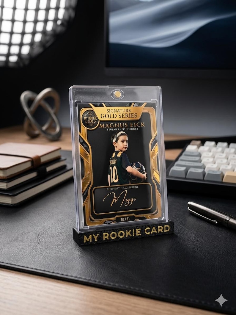 May include: A collectible sports trading card encased in a clear magnetic holder, featuring a young soccer player named Magnus Eick. The card has gold accents, the text "Signature Gold Series," "My Rookie Card," and a signature labeled "Maggi."
