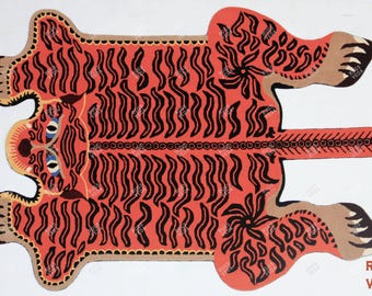 May include: A red and black tiger rug with a detailed design. The rug is made of wool and has a fringed edge. The rug is perfect for adding a touch of whimsy to any room.
