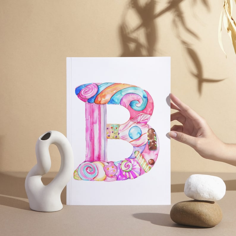 K&ouml;nnte beinhalten: Ein Aquarellbild des Buchstabens B, verziert mit bunten S&uuml;&szlig;igkeiten und Bonbons. Der Buchstabe befindet sich auf wei&szlig;em Hintergrund.