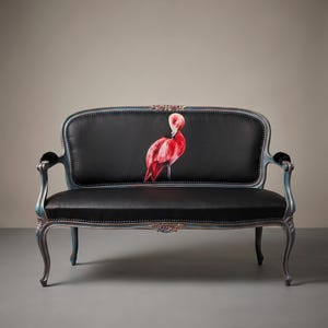 May include: A black loveseat with a flamingo illustration on the backrest. The frame is a distressed blue with ornate carvings. The flamingo is a vibrant red and pink, adding a pop of color to the dark seat.