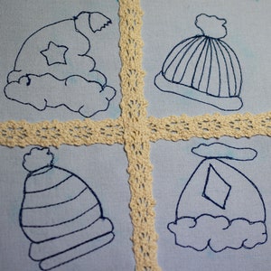May include: Four embroidered blue hats on a light blue fabric background. The hats are decorated with different designs, including a star, stripes, and a diamond.