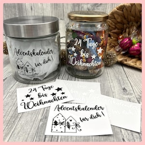 Könnte beinhalten: Zwei Glasgläser mit Deckeln, eines silber und eines gold, gefüllt mit Süßigkeiten und mit schwarzen und weißen Aufklebern verziert. Die Aufkleber sagen "Adventskalender fur dich!" und "24 Tage bis Weihnachten".