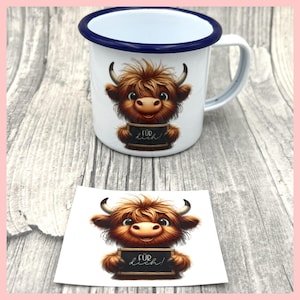 Könnte beinhalten: Weiße Email Tasse mit blauem Rand, auf der eine Comic-Highland-Kuh abgebildet ist, die eine Tafel mit der Aufschrift "Für dich!" hält. Die Tasse steht auf einer Holzoberfläche. Ein Aufkleber mit dem gleichen Design ist ebenfalls abgebildet.
