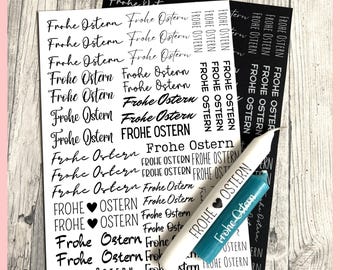 May include: A sheet of white sticker paper with the phrase "Frohe Ostern" repeated multiple times in black lettering. The phrase is written in a variety of fonts and sizes. A teal blue marker with the text "Frohe Ostern" is lying on top of the sticker paper.