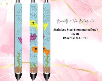 May include: Three stainless steel pens with a blue and white polka dot background. The pens have a floral design with purple, orange, and yellow flowers. The pens are labeled "Beauty & The Bling Co" and "SS 10". The pens are 12 inches across and 45 inches tall.