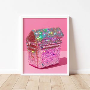 Pode incluir: Impressão emoldurada com uma caixa de correio coberta de glitter em tons de rosa e iridescentes. A caixa de correio está sobre um fundo rosa, dentro de uma moldura branca. A imagem é uma obra de arte vibrante e atraente.