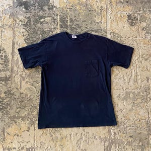 Peut inclure: Un t-shirt bleu marine uni à manches courtes doté d'une encolure ronde et d'une poche plaquée unique sur le côté gauche de la poitrine. Le vêtement présente une coupe standard, des manches courtes et un ourlet droit, affichant un design sobre.