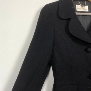 May include: A black blazer with a single button closure and a small pocket on the left side. The blazer has a small, rounded collar and the label "Courr&egrave;ges" is visible on the inside of the collar.