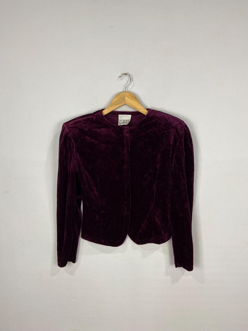 以下が含まれることがあります： ボタン留めと長袖のボルドーベルベットのブレザー。ラベルには「Norma Kamali」と記載されています。