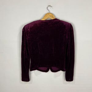 以下が含まれることがあります： 長袖でぴったりとしたシルエットの、濃い赤紫色のベルベットのブレザー。Vネックで、丈が短くなっています。