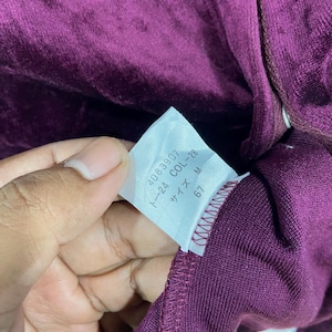 以下が含まれることがあります： 「4089307 1~24 COL~28 サイズ M 67」と黒文字で書かれた白いタグ。タグはワインレッドの生地に付けられています。