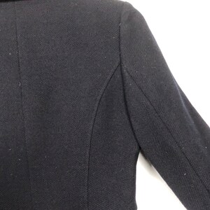 May include: A black blazer with a classic collar and long sleeves. The blazer is made of a textured fabric and has a tailored fit.