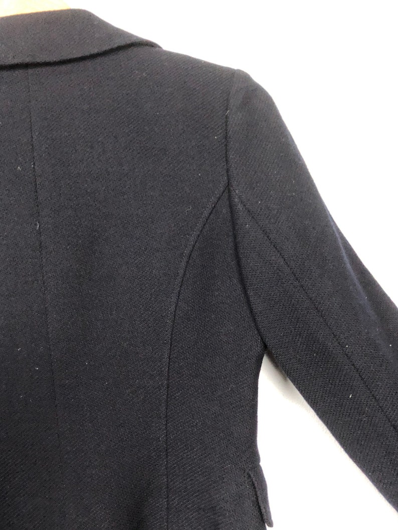 May include: A black blazer with a classic collar and long sleeves. The blazer is made of a textured fabric and has a tailored fit.