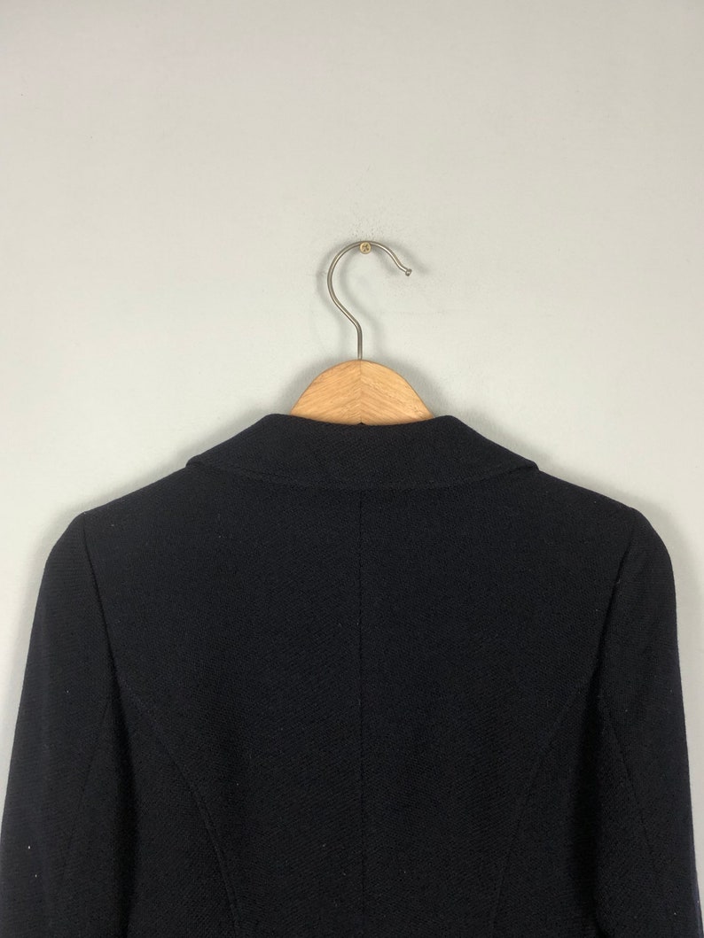 May include: A black blazer hanging on a wooden hanger. The blazer has a classic design with a notched collar and long sleeves.