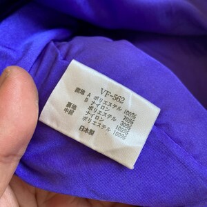 May include: A close-up of a purple fabric with a white tag. The tag has Japanese text and the code "VF-562". The fabric appears to be a lining material, with the tag listing the fabric composition.