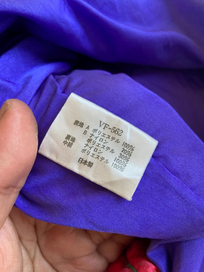 May include: A close-up of a purple fabric with a white tag. The tag has Japanese text and the code "VF-562". The fabric appears to be a lining material, with the tag listing the fabric composition.