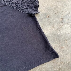 Pu&ograve; includere: T-shirt nero con dettaglio manica in pizzo strutturato. La manica corta &egrave; realizzata in pizzo scuro fantasia. Il resto della maglietta &egrave; di colore nero tinta unita.