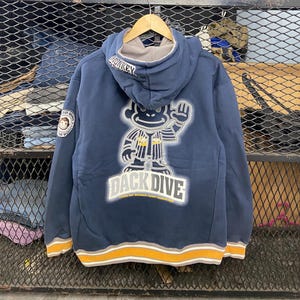 May include: A navy blue hooded sweatshirt with a graphic of a monkey wearing a shirt that says "Back Dive". The monkey is wearing a white shirt with a black design and a black hat. The sweatshirt has a yellow and white stripe at the bottom.