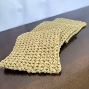 May include: A beige crocheted scarf made with a simple stitch pattern.
