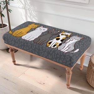 May include: A decorative bench with a gray leopard print pattern and a row of cartoon cats in various colors. The bench has light-colored wooden legs and a rectangular seat.