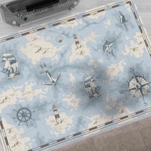 Könnte beinhalten: Ein blauer und weißer Teppich im nautischen Stil mit Kompass, Schiffen, Leuchttürmen und Meereslebewesen. Der Teppich hat einen braunen Rand.