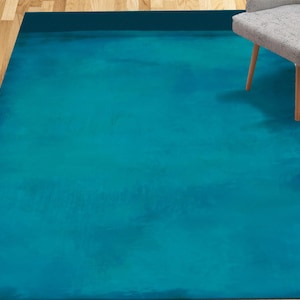 May include: A teal blue area rug with a subtle marbled pattern. The rug is made of a soft, plush material and has a contemporary style.