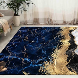 May include: A blue and white area rug with a gold marble design. The rug has a dark blue background with white and gold marble veins. The rug is divided into two sections, one with a blue marble design and the other with a white marble design.