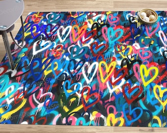Puede incluir: Una alfombra colorida con un diseño de estilo graffiti que presenta muchos corazones en varios colores, incluidos rojo, azul, amarillo, rosa y blanco. Los corazones están pintados sobre un fondo negro.