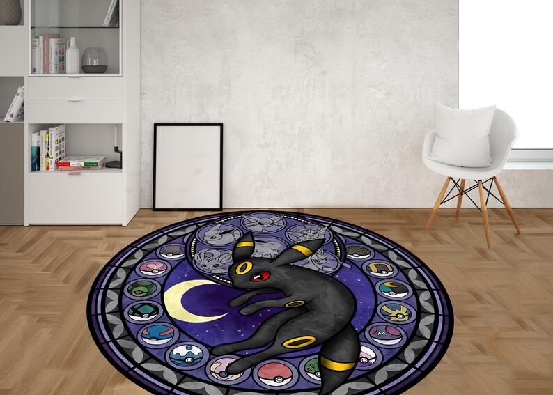 May include: A round, purple and black rug with a stained glass design featuring a black and yellow Pokemon character. The character is surrounded by smaller Pokemon characters in a circle.