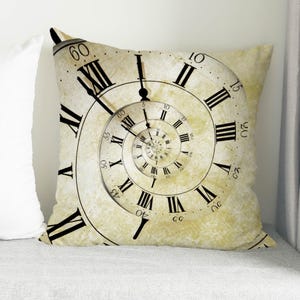 May include: A beige pillow featuring a vintage clock face design. The clock face has Roman numerals and a spiral pattern of clock hands.