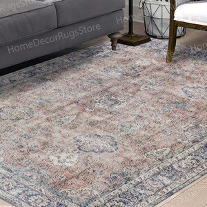 May include: A vintage-style area rug with a faded floral pattern in shades of blue, pink, and cream. The rug has a distressed look and a subtle border.