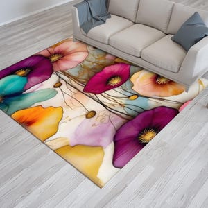 May include: A rectangular area rug featuring a watercolor floral design. The rug showcases large, colorful flowers in shades of purple, pink, orange, and teal against a cream background. The rug is placed on a light gray wooden floor.