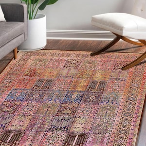 May include: A rectangular area rug with a patchwork design. The rug features a variety of colors including pink, blue, brown, and orange. The rug has a detailed border and is placed on a wooden floor.