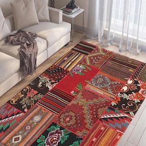 Peut inclure: Un tapis rectangulaire en patchwork avec une variété de motifs et de couleurs. Le tapis présente un mélange de motifs géométriques et floraux dans les tons de rouge, noir, vert et marron. Le tapis est posé sur un sol en bois.