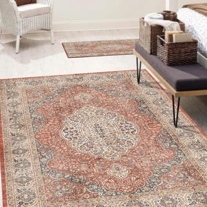 May include: A large, rectangular rug with an ornate, traditional design. The rug features a central medallion in cream and brown, surrounded by a red field with floral and geometric patterns. A smaller runner rug is also visible.