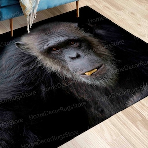 Può includere: Primo piano del viso di uno scimpanzé su uno sfondo nero. Lo scimpanzé ha una pelliccia scura e guarda direttamente la fotocamera. La bocca dello scimpanzé è leggermente aperta, rivelando i suoi denti.