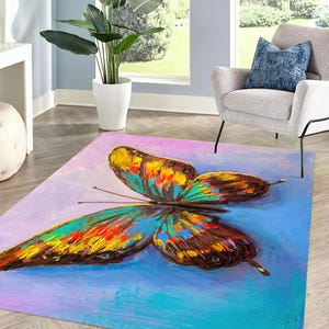 May include: A rectangular area rug featuring a large, colorful butterfly design. The butterfly has wings in shades of yellow, orange, blue, and brown against a background of blue, purple, and pink. The rug is likely made of a soft material.