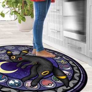 May include: A round, purple and black rug with a stained glass design featuring a black and yellow Pokemon character. The character is standing on a crescent moon with a starry background. The rug is surrounded by a black border.