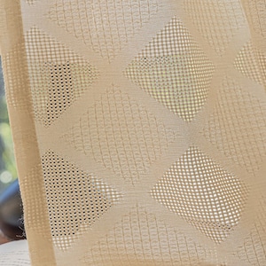 Puede incluir: Primer plano de una cortina transparente de color crema con un patr&oacute;n geom&eacute;trico de c&iacute;rculos y cuadrados superpuestos. La cortina est&aacute; hecha de una tela ligera y transpirable.