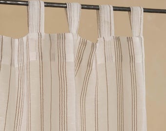May include: Cream-coloured curtain panels with vertical brown stripes. The curtains hang from fabric loops attached to a dark metal rod. The fabric has a slightly textured appearance, creating a soft, natural look.